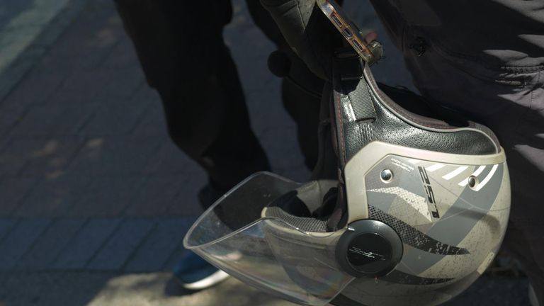 A suspected illegal immigrant working as a delivery driver holds his helmet 

