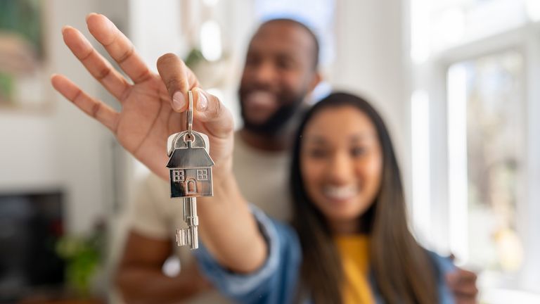 Happy couple of homeowners holding the keys of their new house ... real estate concepts