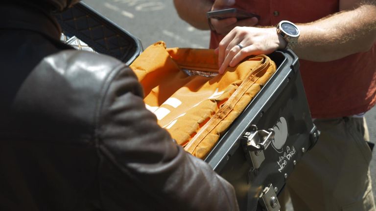 A man inspects the Just Eat food delivery bag of a suspected illegal immigrant working as a delivery driver  
