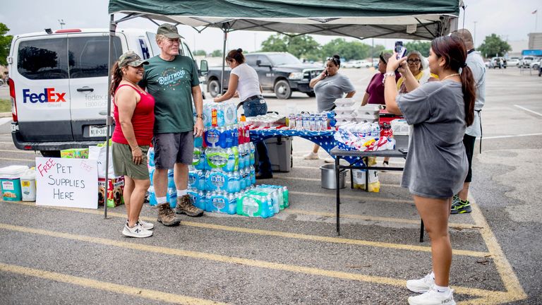 A man takes a photo with Claudia Rodriguez as her family distributes free supplies and home-cooked meals.
Pic: Reuters