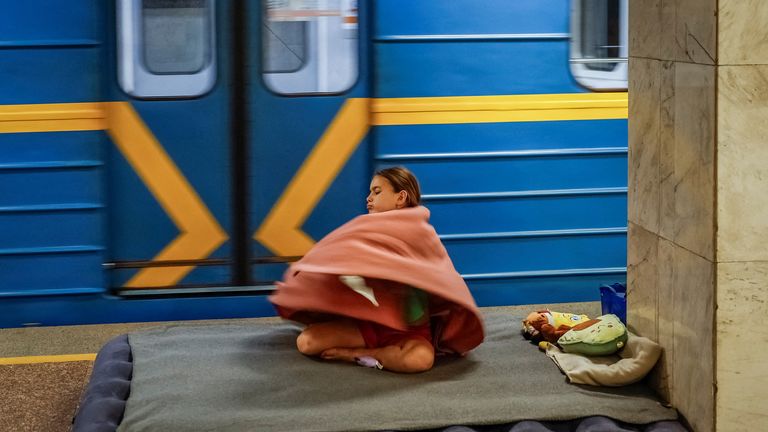 A girl covers herself with blanket as she takes shelter inside a metro station during an air raid alert in Kyiv.
Pic: Reuters