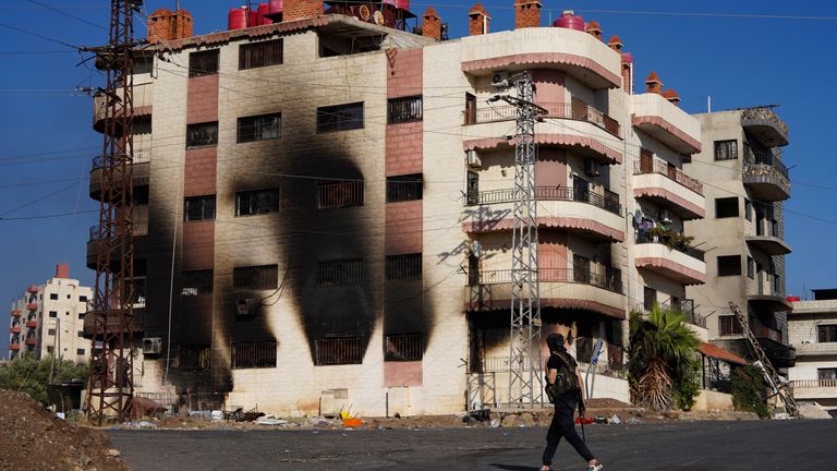 Bir Bedevi savaşçısı, mezhepli çatışmalardan sonra yanmış bir binanın yanında yürür.  Pic: Reuters/Karam Al-Masri