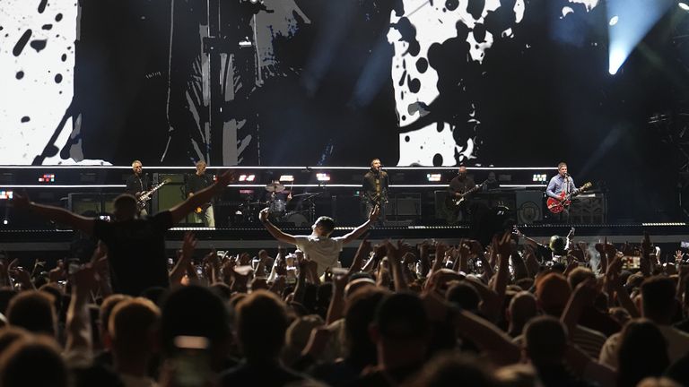 Two fans sat on their friends' shoulders as Oasis performed. Pic: PA