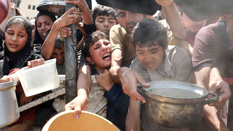 Palestinians wait to receive food from a charity kitchen, amid a hunger crisis, in Gaza City, July 28, 2025. REUTERS/Khamis Al-Rifi