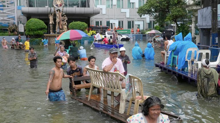 Residents wade along a flooded road as Typhoon Co-may intensified seasonal monsoon rains at Malabon city, Philippines on Friday, July 25, 2025. (AP Photo/Aaron Favila)