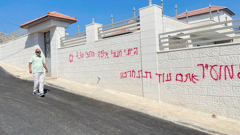 A Palestinian man walks next to a wall covered with sprayed Hebrew slogans. Pic: Reuters