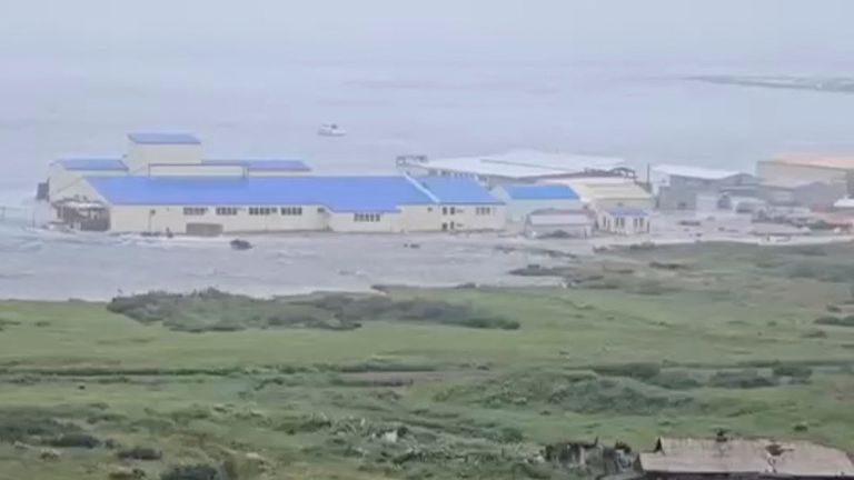 A powerful wave washes past a building located near the shore, after a powerful earthquake struck off the Kamchatka Peninsula, in Severo-Kur