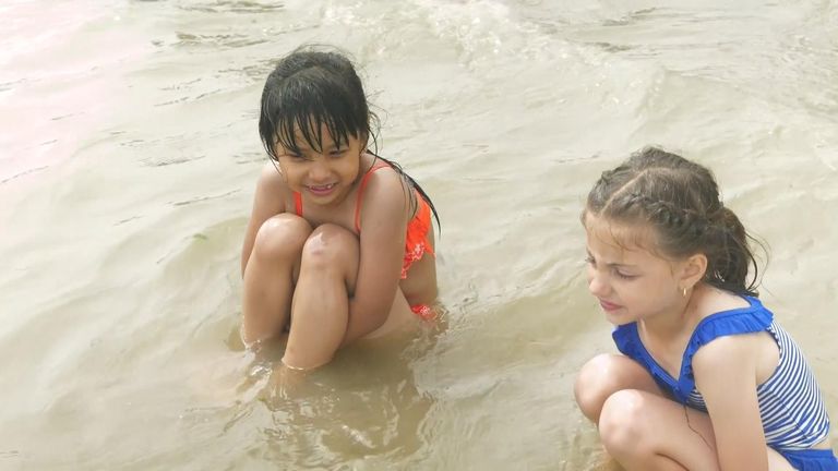 Two girls chat as they sit in the water