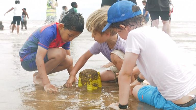 Three boys play with wet sand