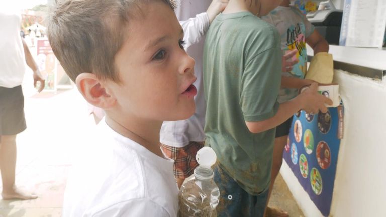 A boy holds a water bottle filled with sand
