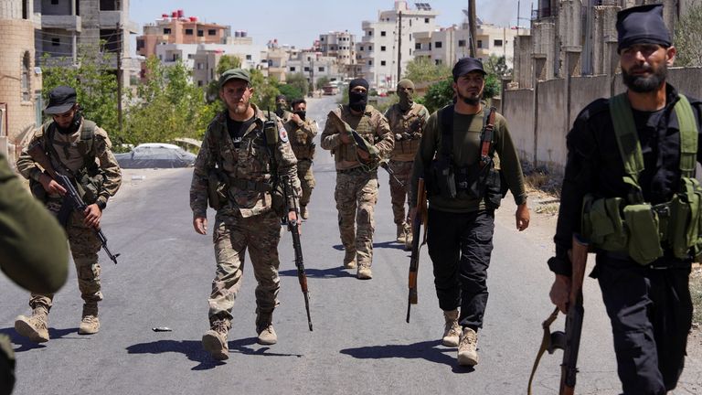 Syrian security forces walk together along a street in the southern Druze city of Sweida.
Pic: Reuters