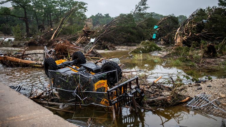 An overturned vehicle is caught in debris along the Guadalupe River after a flash flood struck the area, Friday, July 4, 2025, in Kerrville,