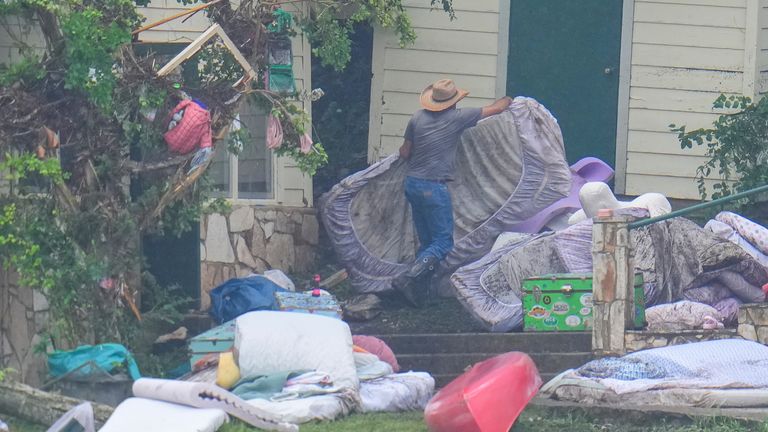 A person removes bedding from sleeping quarters at Camp Mystic. Pic: AP/Julio Cortez