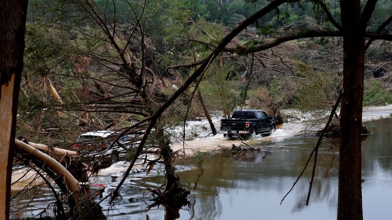 Vehicles ride through a flooded road, following flash flooding, in Hunt, Texas. Pic: Reuters/Marco Bello