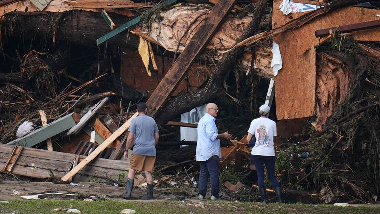 People look at debris on the banks of the Guadalupe River after a flash flood swept through the area Saturday, July 5, 2025, in Hunt, Texas. (AP Photo/Julio Cortez)