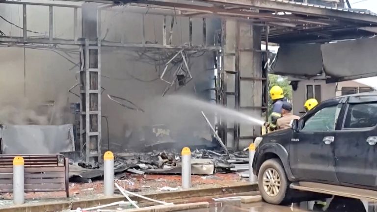 Firefighters work to extinguish fire at a convenience store at a petrol station in Kantharalak, Thailand.
Pic: TPBS/Reuters