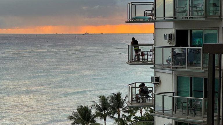 Vacationers stand on balconies at the Aston Waikiki Circle Hotel looking towards Waikiki Beach after authorities warned of the possibility o