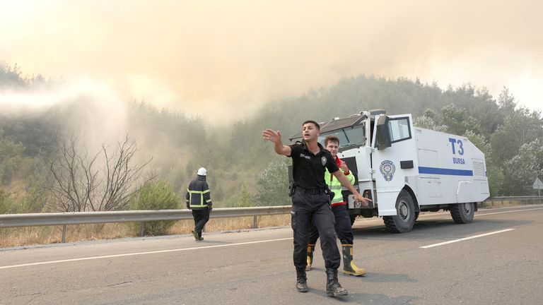 Bir polis memuru, Osmanel yakınlarındaki bir orman yangını sırasında itfaiyecilerin gelişinden önce bölgeyi temizler, Türkiye Pic: Reuters