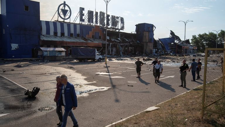 Employees walk past a damaged shopping centre in the city of Kamianske in the Dnipro region. Pic: Reuters