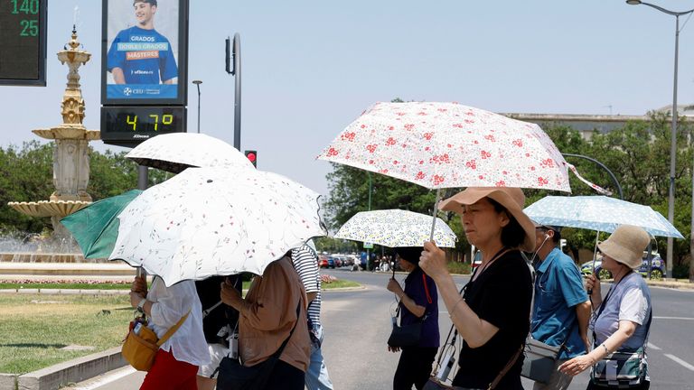 As pessoas usam os guarda -chuvas perto do termômetro para mostrar 47 graus Celsius com um calor quente de Sevilha, Espanha. Imagem: Reuters