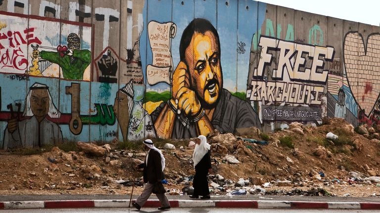 Palestinians walk by a portrait of jailed Marwan Barghouti near the West Bank city of Ramallah. File pic: AP