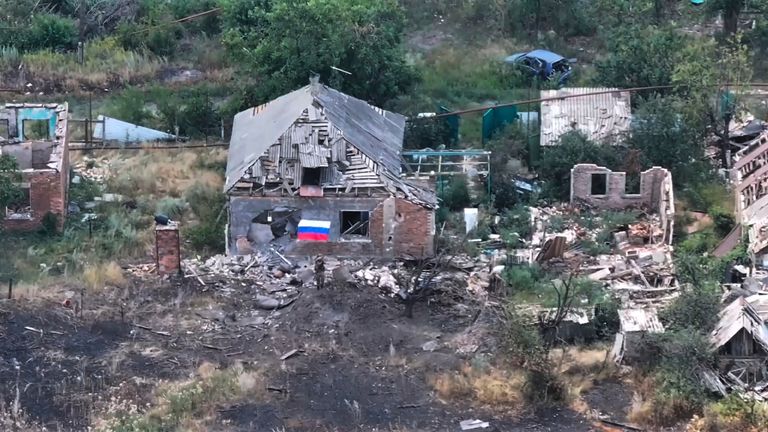 Um soldado russo acena uma bandeira russa entre edifícios arruinados na cidade de Chasiv Yar. Foto: Ministério da Defesa Russa/AP