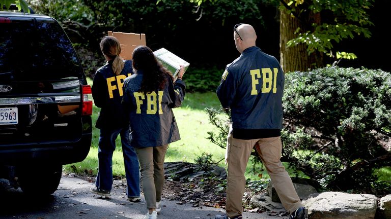 FBI members carry boxes outside the home of the former White House national security adviser John Bolton.
Pic: Reuters