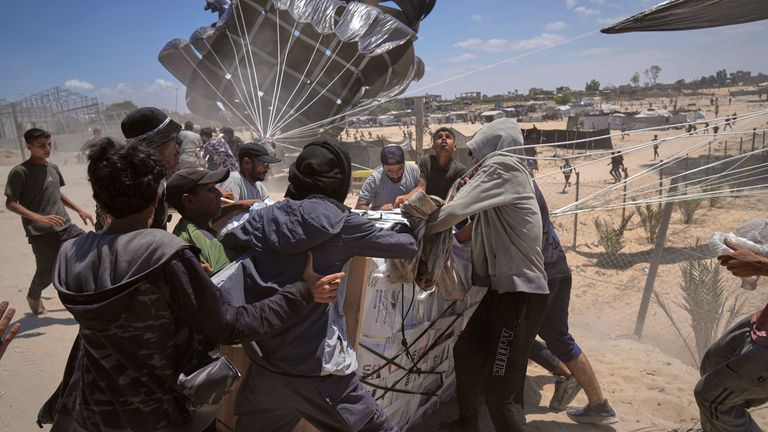 Palestinians rush to collect humanitarian aid airdropped by parachutes into Deir al-Balah, central Gaza Strip, Tuesday, Aug. 5, 2025. (AP Photo/Abdel Kareem Hana)