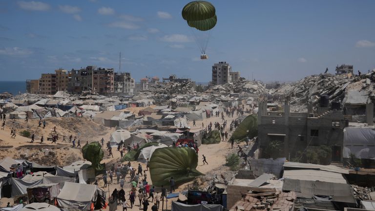 Palestinians rush to collect aid airdropped by parachutes into Gaza City. Pic: AP