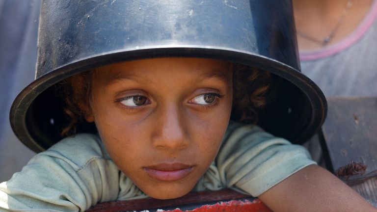 A Palestinian child waits to receive food from a charity kitchen. Pic: Reuters