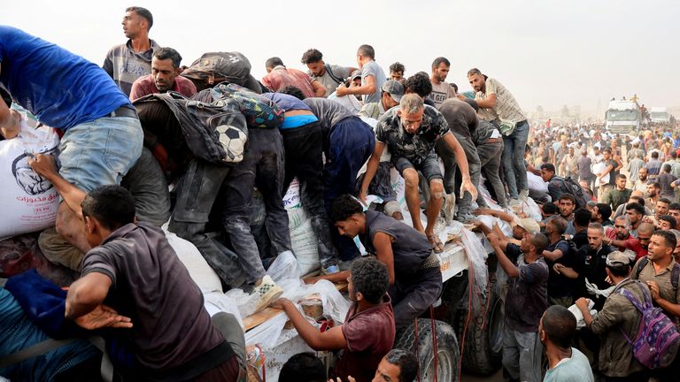 Palestinians scramble to collect aid from trucks that entered through Israel, in Khan Younis. Pic: Reuters
