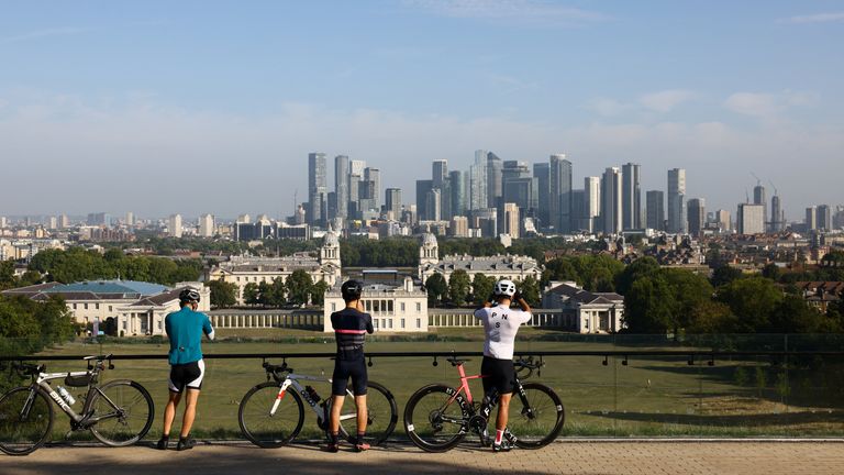 Cyclists take pictures of the skyline from Greenwich Park. Pic: Reuters