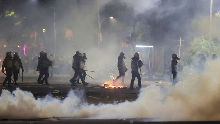 Police officers walk amid tear gas. Pic: AP/Trisnadi