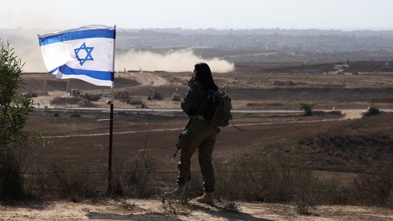An Israeli soldier, standing next to an Israeli flag, looks out across Gaza. Pic: Reuters