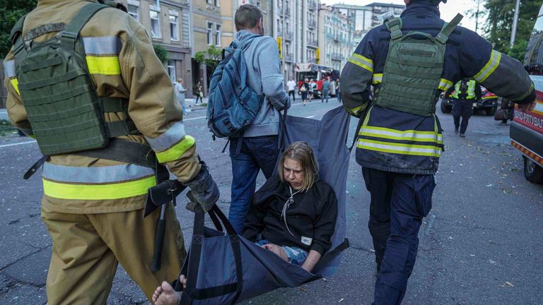 Rescue workers carry an injured woman after a Russian strike on Kyiv, Ukraine. Pic: AP
