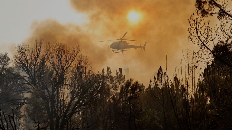 A helicopter drops water on a wildfire in Larouco. Pic: AP