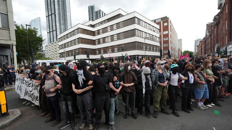 Masked protesters gather outside the Thistle City Barbican Hotel in central London, which houses asylum seekers. Pic: PA
