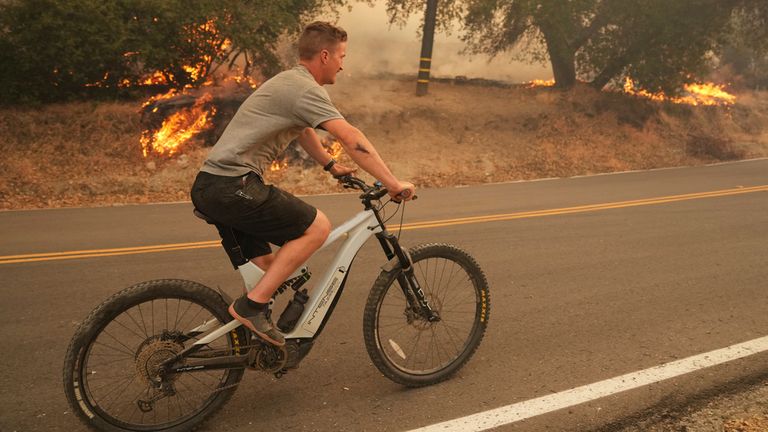 Mieszkaniec jeździ na rowerze przez pożary w Hasley Canyon. PIC: AP
