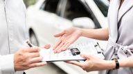 A stock image of someone signing a car rental agreement with an out-of-focus car behind them.
Pic: iStock