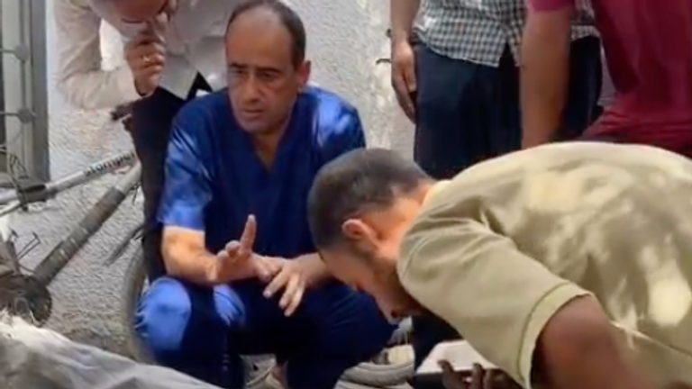 Dr Mohammed Abu Salmiya kneels next to the body of one of his relatives