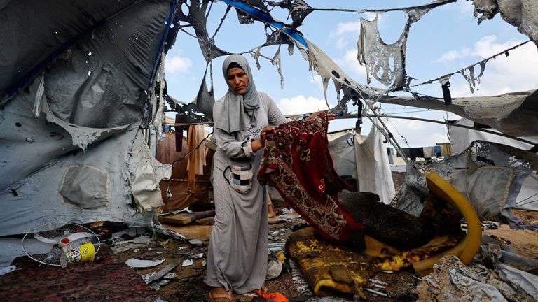 A Palestinian woman carries a prayer mat at the site of an overnight Israeli strike on a tent, in Gaza City.
Pic: Reuters