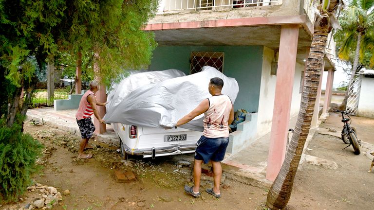 Men cover a car to protect it from Hurricane Melissa in Santiago de Cuba on Tuesday. Pic: Reuters
