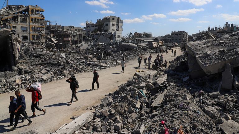Palestinians walk past the rubble of destroyed buildings in Gaza City. Pic: Reuters