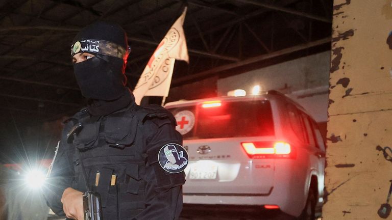 A Hamas militant stands guard as a Red Cross vehicle arrives to receive the bodies of deceased hostages. Pic: Reuters