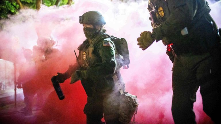 Police and federal officers throw gas canisters to disperse crowds on Sunday protesting at immigration crackdowns in Portland. Pic: AP