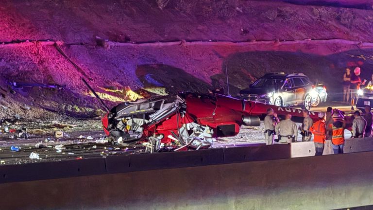 Law enforcement officers stand near the wreckage of the helicopter. Pic: AP
