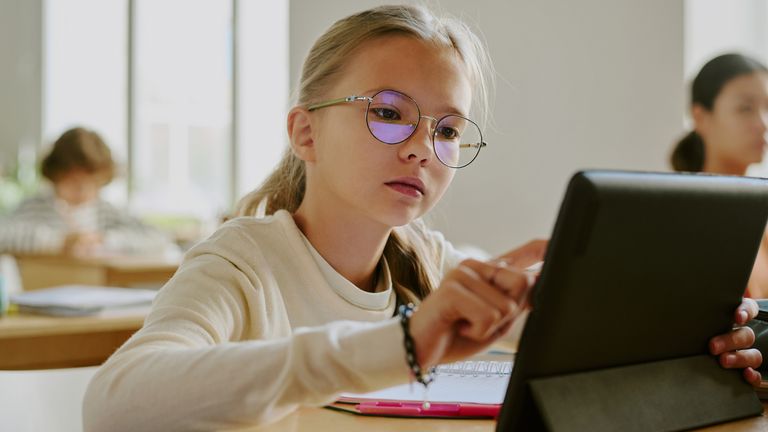 Dziewczyna korzystająca z tabletu w szkole. Zdjęcie: iStock