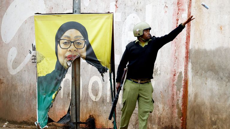 A Tanzanian riot police officer throws a tear gas canister near a torn campaign poster of President Samia Suluhu Hassan. Pic: Reuters
Pic Reuters