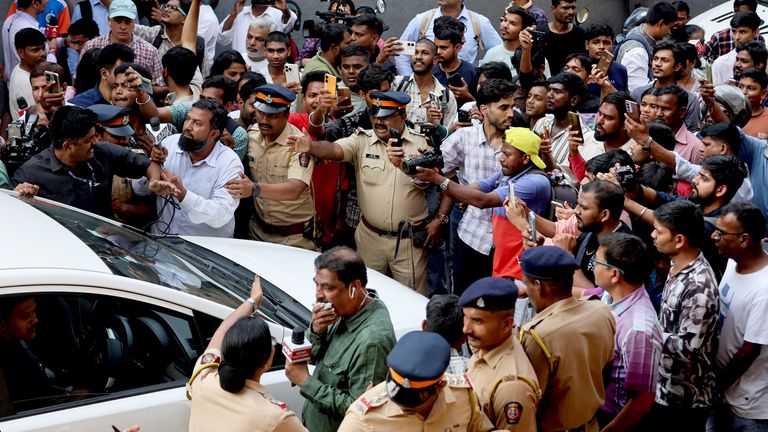 Police officers attempt to control a crowd as they surround a car exiting the crematorium after the death of Dharmendra. Pic: Reuters