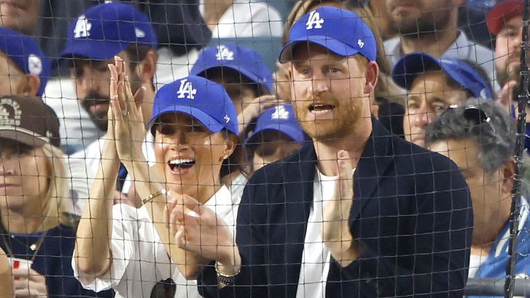 Prince Harry and his wife, Meghan, in LA Dodgers caps at the game. Pic: John Angelillo/UPI/Shutterstock